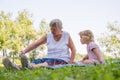 Grandmother with her grandaughter casually sitting on a blanket reading and talking in a park. Royalty Free Stock Photo