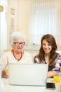 Grandmother and her granddaughter having fun with laptop at home. Royalty Free Stock Photo