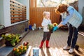 Grandmother with her little granddaughter gardening in a backyard. Different generation. Grandmawith and granddaughter planting.