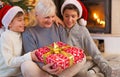 Grandmother With Her Two Grandchildren, Holding A Christmas Gift Royalty Free Stock Photo