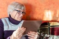 Grandmother holding digital device and sitting on couch at home