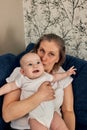 grandmother hugs and plays with her little grandson, sitting on a blue sofa in a bright room. Happy loving family. Royalty Free Stock Photo