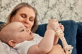 grandmother hugs and plays with her little grandson, sitting on a blue sofa in a bright room. Happy loving family. Royalty Free Stock Photo