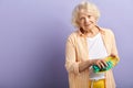 Grandmother keeping hosehold. Senior woman cleaning bowl isolated on purple.