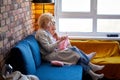 Grandmother Knitting Scarf WIth Grandgranddaughter In Living Room At Home