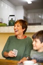 Grandmother laughing while playing cards sitting on a table Royalty Free Stock Photo