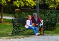 Grandmother with little girl sitting on a wooden bench in the park in Bucharest, Romania, 2019