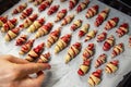 Grandmother making handmade tasty butter rolling cookies with fruit and berry jam on oven tray before baking at kitchen Royalty Free Stock Photo