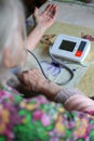Grandmother measures pressure with an apparatus electronic tonometer