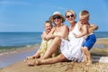 Grandmother, mother and children are resting on the seashore on a bright sunny day. Happy family hugging and laughing. Love and