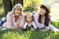 Grandmother, mother and grand daughter enjoying sunny garden holiday together outdoors, lying on green grass on blanket Royalty Free Stock Photo