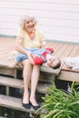 Grandmother playing with grandson boy on porch at home backyard. Bonding of relatives and generation communication. Old woman with Royalty Free Stock Photo