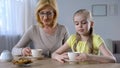 Grandmother and pretty little girl drinking tea with cookies, family traditions Royalty Free Stock Photo