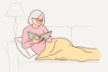 Grandmother is reading book sitting on couch, covering legs with blanket and enjoying exciting plot