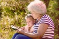 Grandmother reading to her granddaughter child book outdoors. Happy family concept Royalty Free Stock Photo