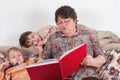 Grandmother reads an interesting, big, red book for grandchildren