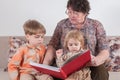 Grandmother reads a large red book for grandchildren