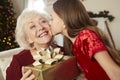 Grandmother Receiving Christmas Gift From Granddaughter At Home Royalty Free Stock Photo