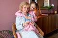 grandmother showing daughter how to knit from yarn sitting on chair Royalty Free Stock Photo