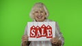 Grandmother showing Sale word inscription note, satisfied with low prices, shopping on Black Friday