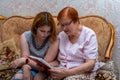 The grandmother shows her granddaughter her old photos from the family album. A happy family Royalty Free Stock Photo