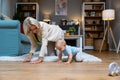 Grandmother of single mother taking care of her young baby, playing on the apartment floor. Senior woman babysitting her grandson Royalty Free Stock Photo