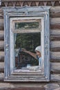 Grandmother sits at a window in the old house in the village in Russia