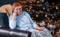 Grandmother sitting on the chair with book in festive New year room with christmas decorations Royalty Free Stock Photo