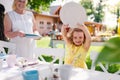 Grandmother and small girll outdoors on garden party in summer, setting table.