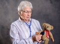 Grandmother with stethoscope is puppet doctor for teddy bear Royalty Free Stock Photo