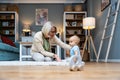 Grandmother taking care of her grandchild while his parents working. Senior woman work as a nanny, playing with young baby on the
