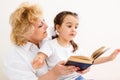 Grandmother teaches to read a book granddaughter