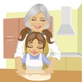 Grandmother teaching granddaughter how to roll out dough to cook pizza in kitchen Royalty Free Stock Photo