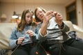 Grandmother and teenage granddaughter knitting on a sofa. Grandma teaching teen child to knit