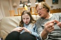 Grandmother and teenage granddaughter knitting on a sofa. Grandma teaching teen child to knit