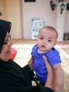 Grandmother wearing hijab is playing with her baby granddaughter