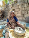 grandmother working on old stone wheel flour mill and making chickpeas wheat.