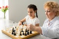 Grandmother and young girl playing chess together at home