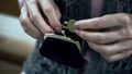 Grandmothers trembling hand putting coin in wallet, pensioner poverty, closeup Royalty Free Stock Photo