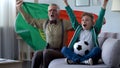 Grandpa and grandson watching football, waving Portuguese flag, happy for win Royalty Free Stock Photo