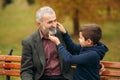 Grandpa and his grandson spend time together in the park. They are sitting on the bench. Walking in the park and Royalty Free Stock Photo