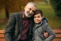 Grandpa and his grandson spend time together in the park. They are sitting on the bench. Walking in the park and Royalty Free Stock Photo