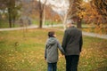 Grandpa and his grandson spend time together in the park. They are sitting on the bench. Walking in the park and Royalty Free Stock Photo