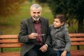 Grandpa and his grandson spend time together in the park. They are sitting on the bench. Walking in the park and Royalty Free Stock Photo