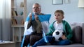 Grandpa holding Argentina flag, watching football with boy, worrying about game Royalty Free Stock Photo