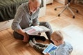 Grandpa looks photo album with his wedding, little boy using electronic tablet