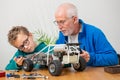 Grandpa and son little boy repairing model radio-controlled car at home