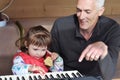 Grandpa teaches little girl to play piano. Concept of music study and creative hobby