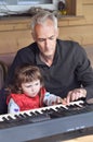 Grandpa teaches little girl to play piano. Concept of music study and creative hobby