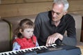 Grandpa teaches little girl to play piano. Concept of music study and creative hobby